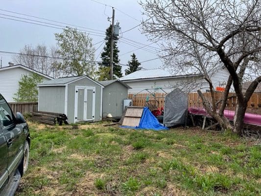 A truck is parked in a yard next to a shed.
