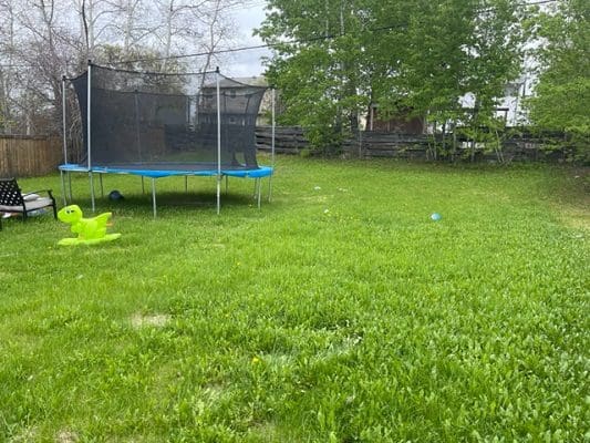 A backyard with a trampoline and chairs.