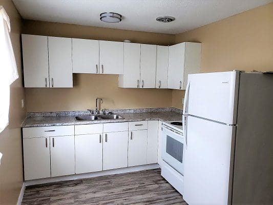 A kitchen with white cabinets and a refrigerator.