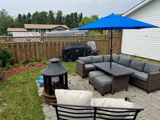 A backyard with patio furniture and an umbrella.