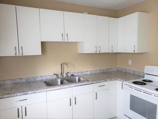 A kitchen with white cabinets and granite counter tops.
