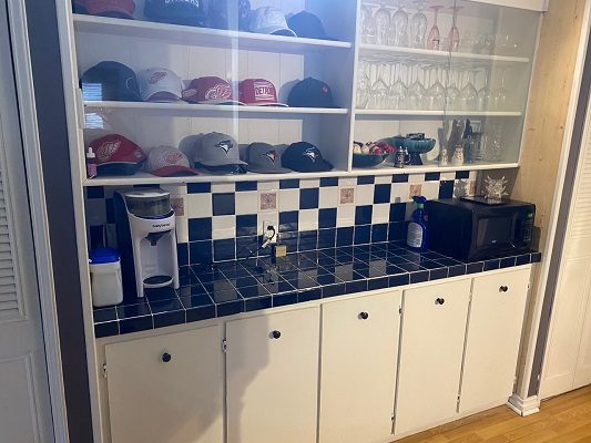 A kitchen with a refrigerator, sink, and a hat rack.