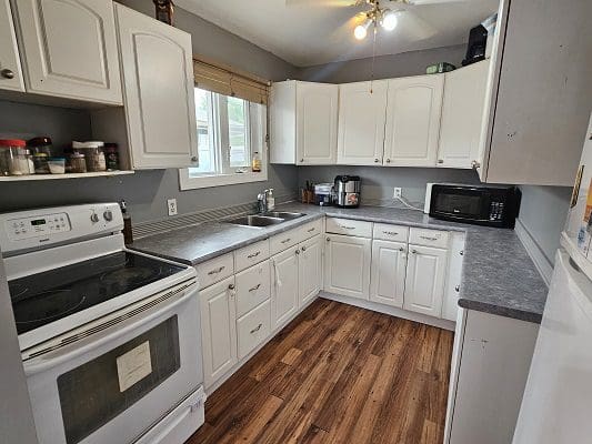 A kitchen with white cabinets and hardwood floors.