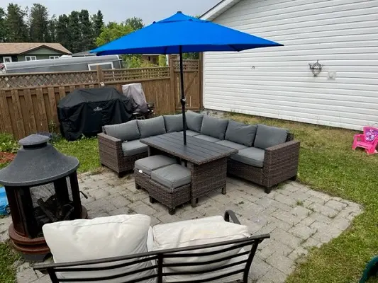 A backyard with a blue umbrella and patio furniture.