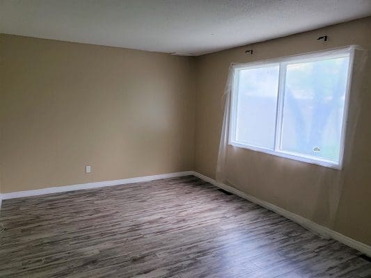 Empty room with hardwood floors and a window.