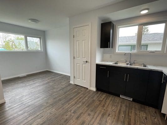 An empty kitchen with wood floors and a window.