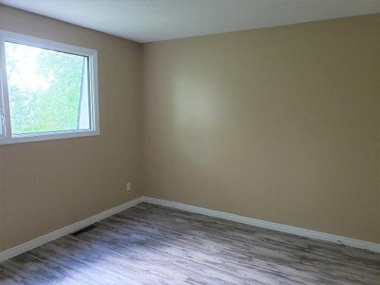 An empty room with wood floors and a window.