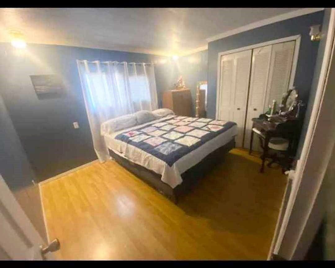 A bedroom with blue walls and hardwood floors.