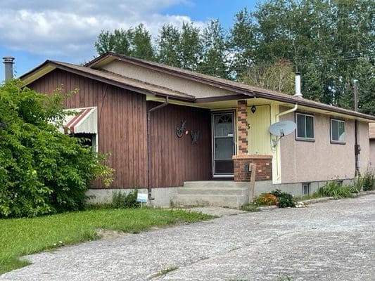 Ranch house with brown siding and yard.