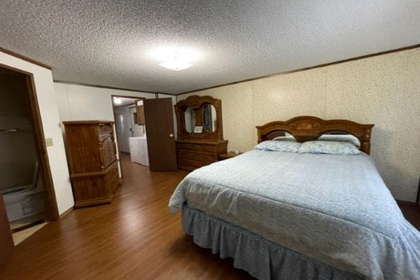Bedroom with queen bed and wood furniture.