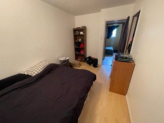 Bedroom with bed, shelf, and doorway.