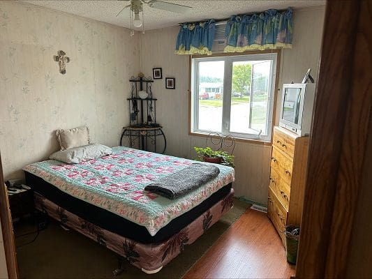 Bedroom with floral quilt and dresser.