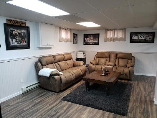 Finished basement with brown recliners and rug.