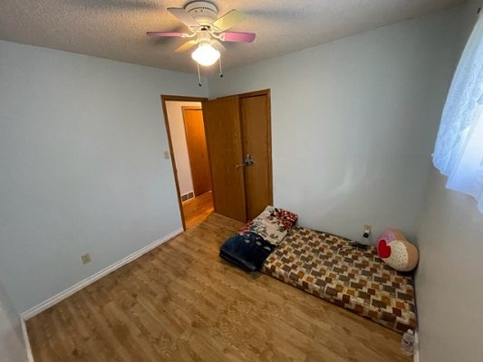 An empty room with a bed and a ceiling fan.