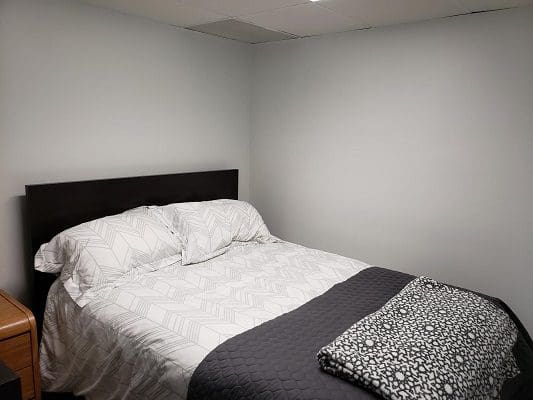 Bedroom with bed and grey blanket.