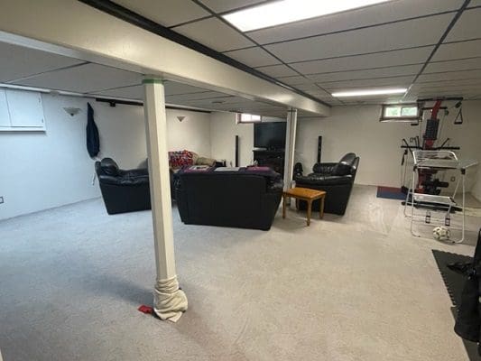 Finished basement with furniture and gym equipment.