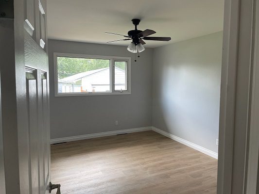 An empty room with hardwood floors and a ceiling fan.