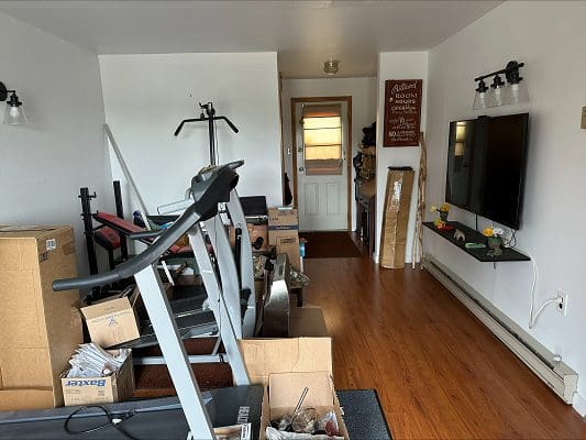 Home gym with treadmill and TV.