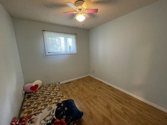 A small room with hardwood floors and a ceiling fan.