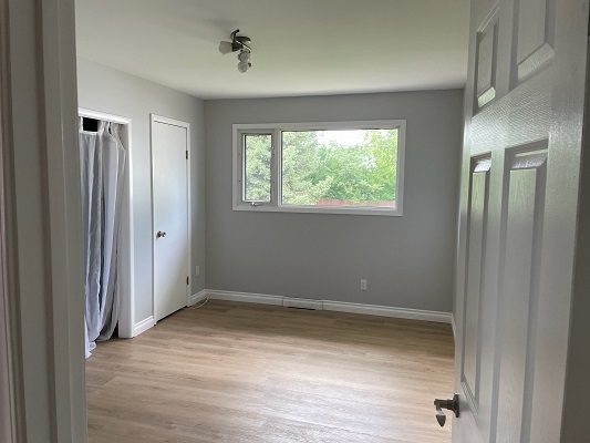 An empty room with hardwood floors and a window.