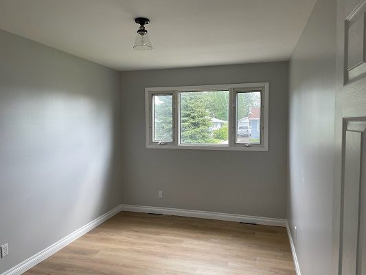 An empty room with wood floors and a window.