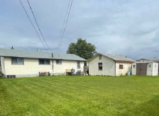 Houses and shed in grassy yard.