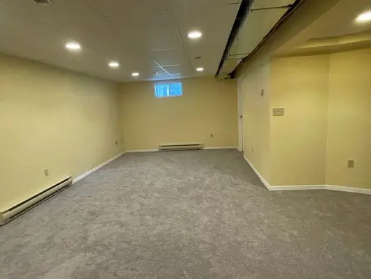 An empty room with carpet and a ceiling fan.