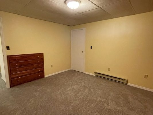 An empty room with yellow walls and a dresser.