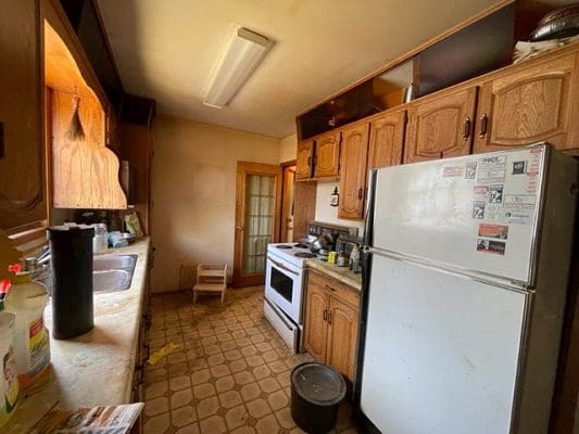 Old kitchen with wood cabinets and fridge.