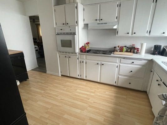 White kitchen with light wood floor.