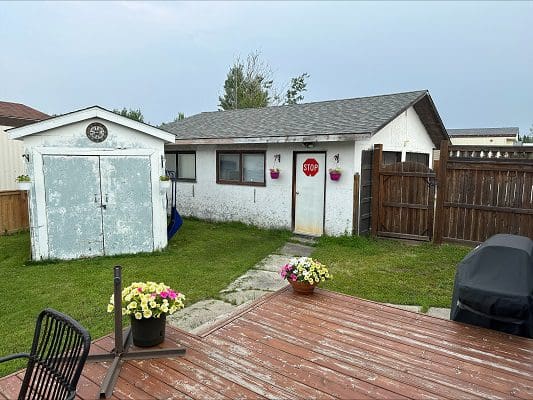 White house with detached shed and deck.