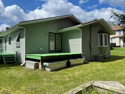 A house with a deck and a green lawn.