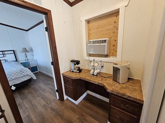 Coffee station with mini-fridge and bedroom view.