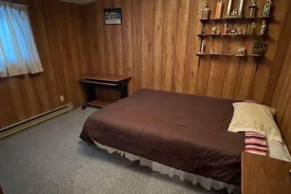 Bedroom with bed, desk, and trophies.