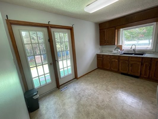 An empty kitchen with wooden cabinets and a window.
