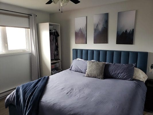 Blue bedroom with king-size bed and art.