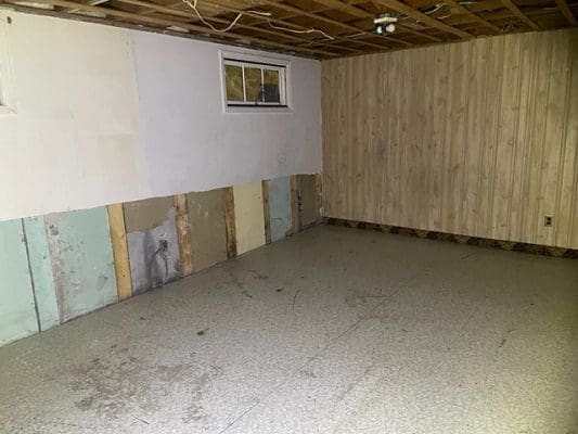 Basement with water damage and wood paneling.