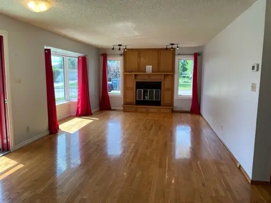 An empty living room with hardwood floors and a fireplace.