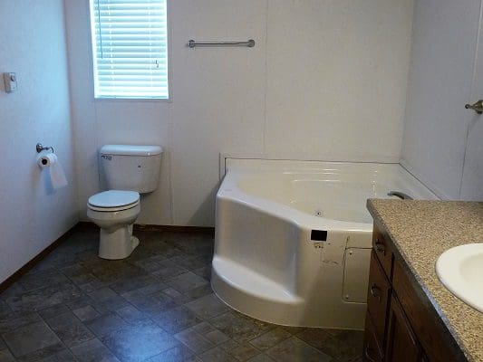 Bathroom with toilet and corner tub.