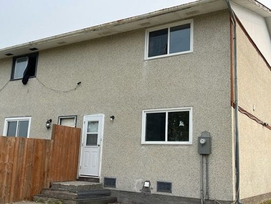 Tan stucco townhouse exterior with windows.