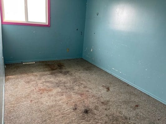 Dirty room with stained carpet and walls.