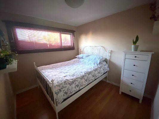 Bedroom with white metal bed and dresser.