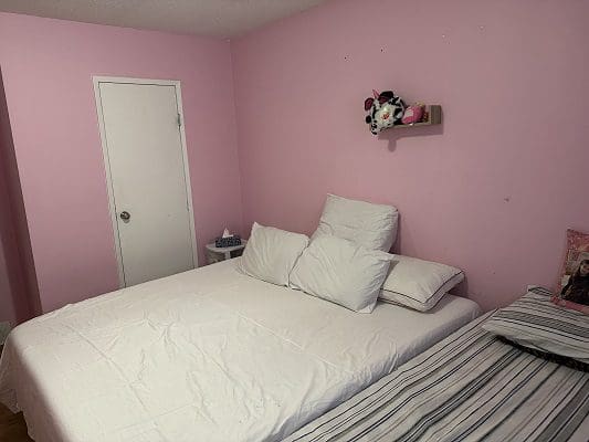 Pink bedroom with white bedding and two beds.