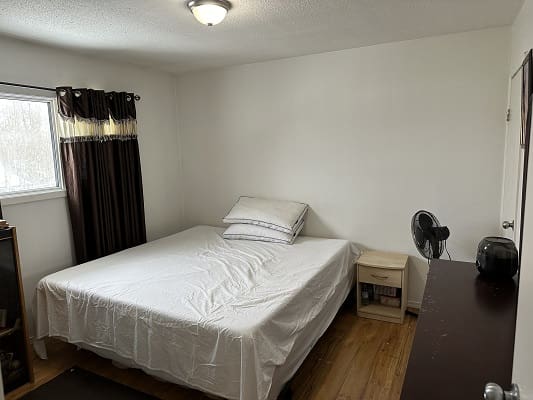 Bedroom with bed, window, and nightstand.