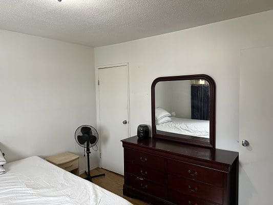 Bedroom with dresser, mirror, and bed.