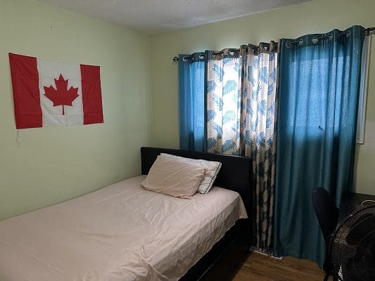 Canadian flag, bed, and teal curtains.