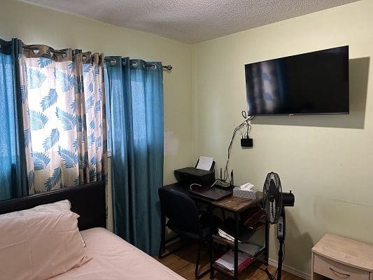 Bedroom with bed, desk, and TV.
