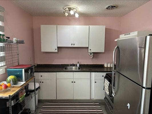 Pink kitchen with white cabinets and appliances.