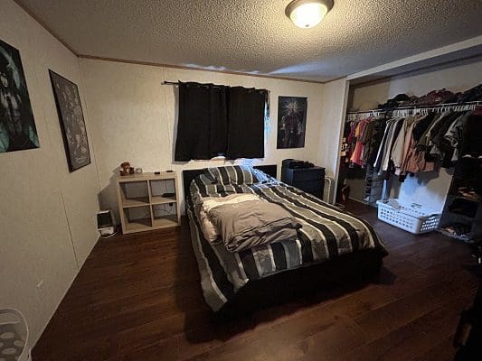 Bedroom with bed, closet, and wood floor.
