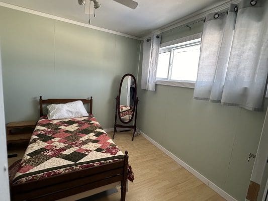 Bedroom with bed, mirror, and window.